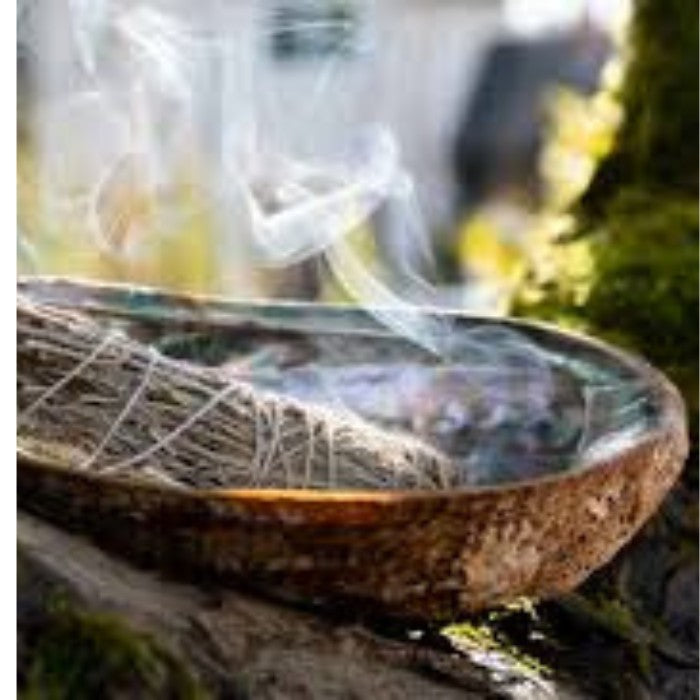 Alt tag: Burning Sage Smudge Stick in a bowl, a cleansing and purifying product traditionally used to clear negative energy and promote balance.