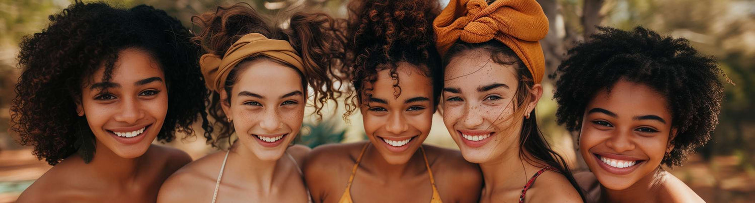 A panoramic view of five diverse young women with joyful expressions, each showcasing unique hairstyles and radiant smiles, symbolizing the vibrant and inclusive spirit of The Good Stuff Health Shop South Africa, part of the TERRA NOVA Collection.
