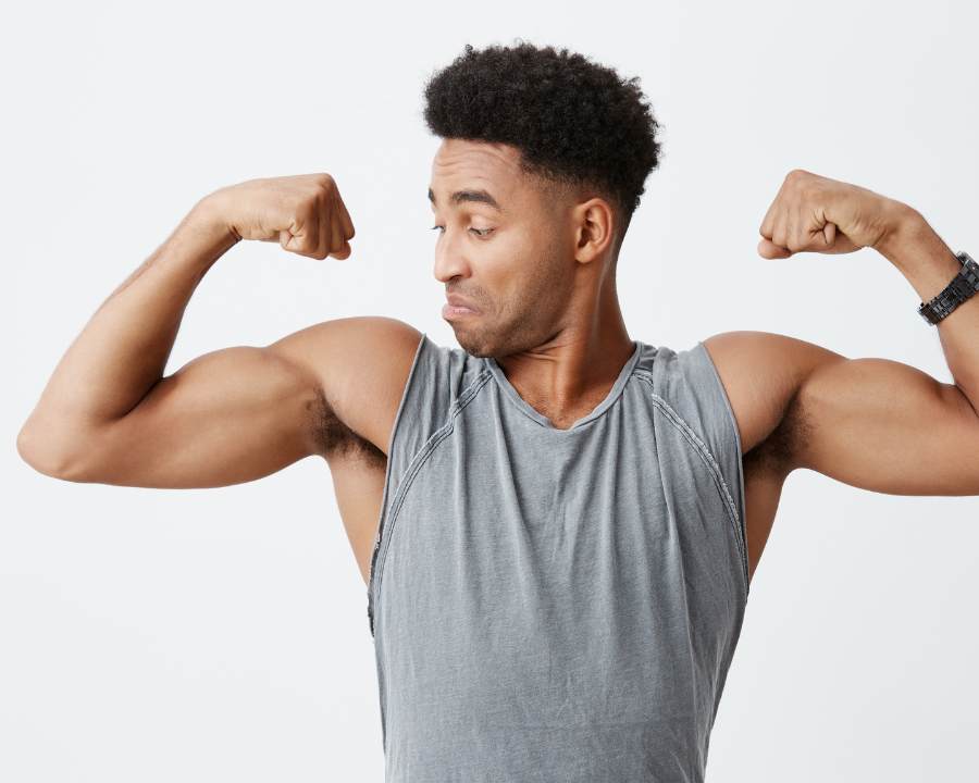 Man flexing muscles in grey tank top representing best supplements for muscle growth – The Good Stuff fitness and wellness range