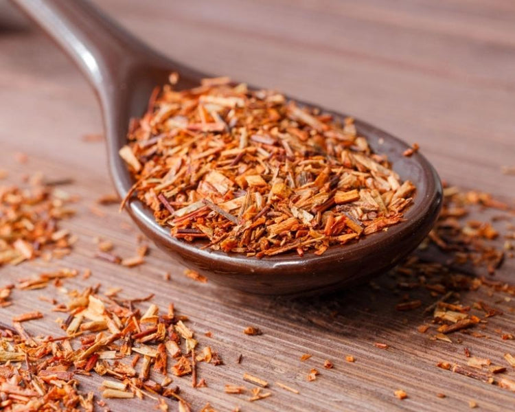 Rooibos tea leaves on a wooden spoon — loose leaf Biedouw Valley rooibos, warm copper colour, ready for brewing