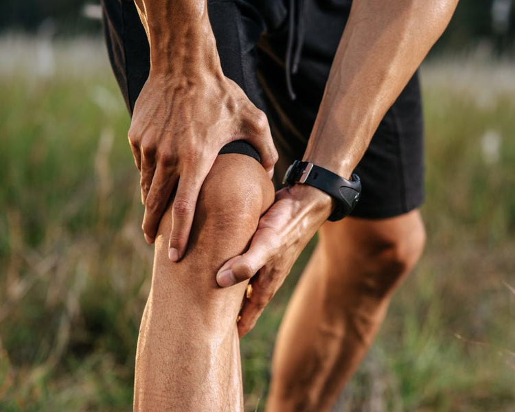 Bones and Joints - The Good Stuff – runner clutching knee outdoors; joint pain relief and mobility support.