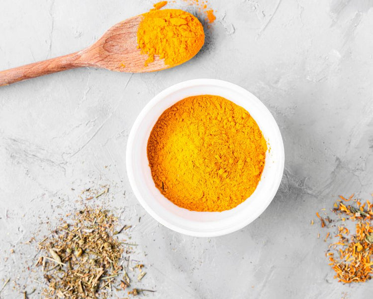 Bright turmeric curcumin powder in a white bowl with wooden spoon — Curcumin Supplements collection by The Good Stuff.