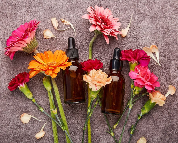 Amber dropper bottles with colourful fresh flowers on a grey background – Flower Essences from The Good Stuff South Africa
