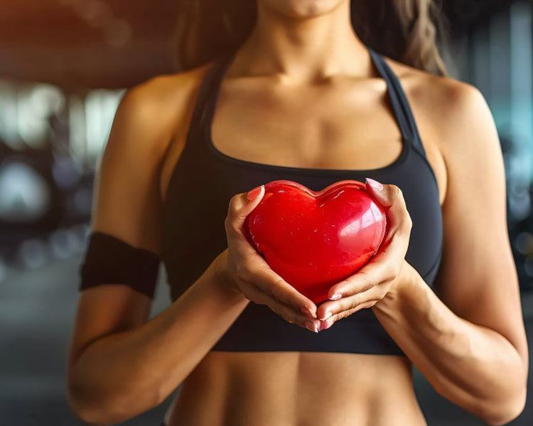 Woman in sportswear holding a red heart symbol representing cardiovascular wellness – Heart Health Supplements by The Good Stuff
