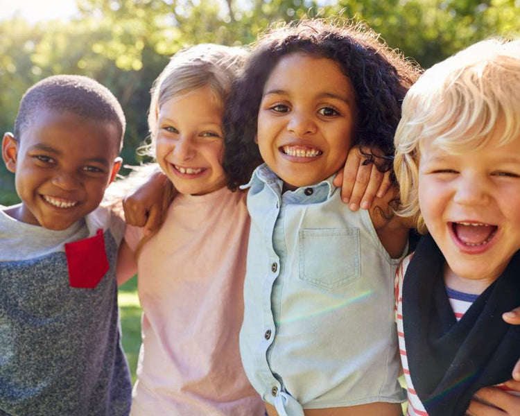 Kid's Supplements - The Good Stuff – happy diverse children hugging outdoors; daily vitamins for minds and bodies.