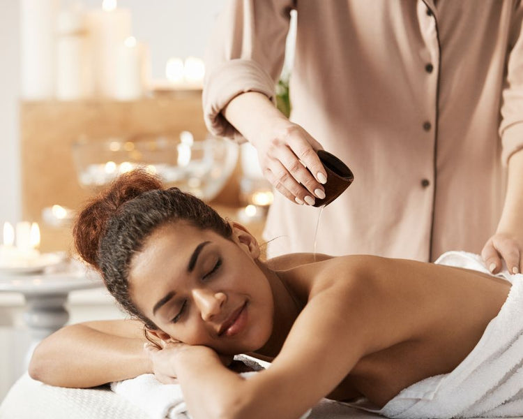 Massage Oil – woman relaxing during back massage with warm oil in spa setting, promoting calm and self-care.