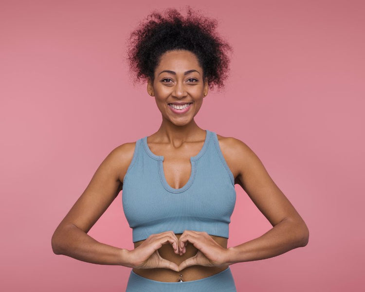 Woman forming a heart over her tummy on pink background — positive digestion and wellbeing, aligned with Parasite Cleanse goals.