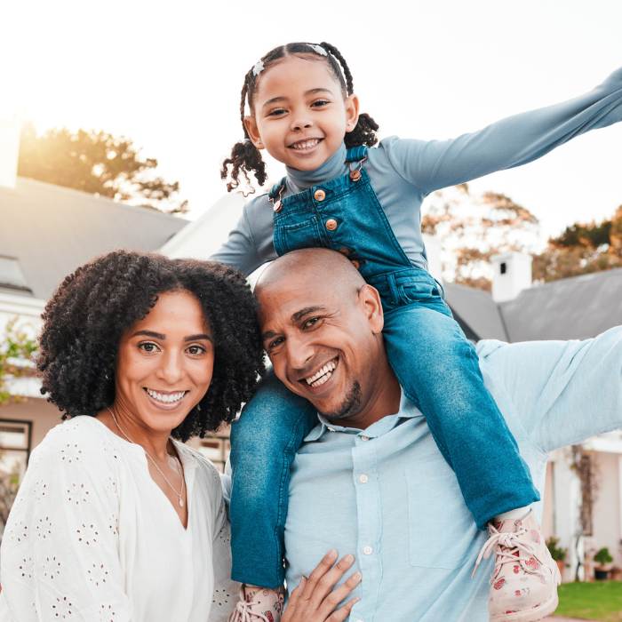 Happy family outdoors with child on dad’s shoulders – promoting gut health and probiotics from The Good Stuff.