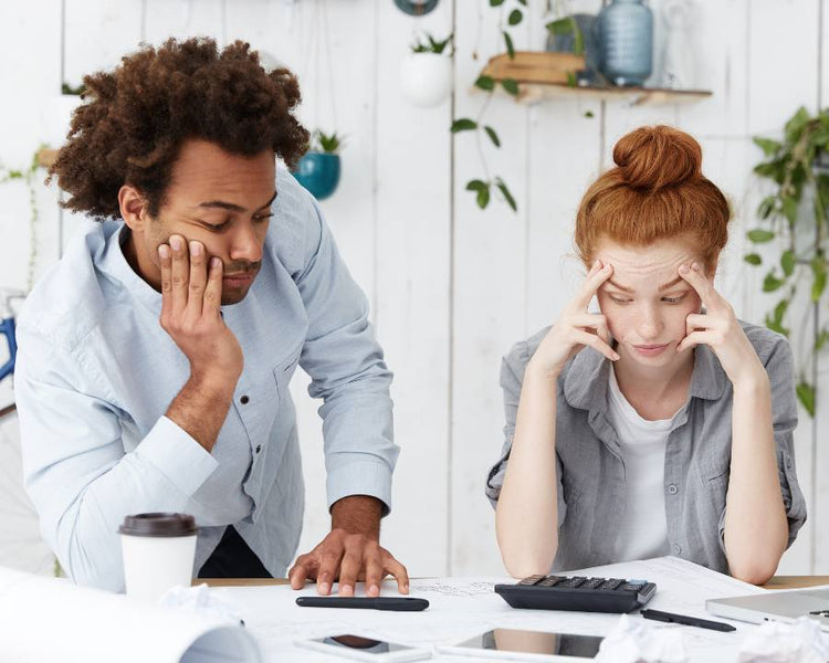 Stress & Anxiety Supplements - The Good Stuff – stressed couple at desk with bills and calculator, seeking calm and focus.